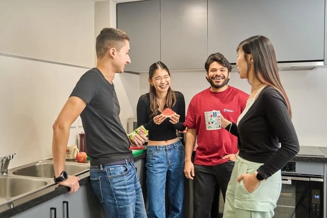 Students laughing holding watermelon and drinks kitchen area at Campus Melbourne in Melbourne Student Accommodation