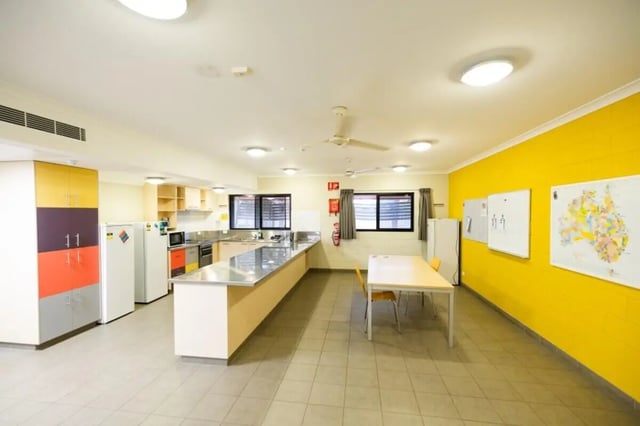 Kitchen with long counter two fridges and table. at CDU Village Casuarina in Darwin Student Accommodation