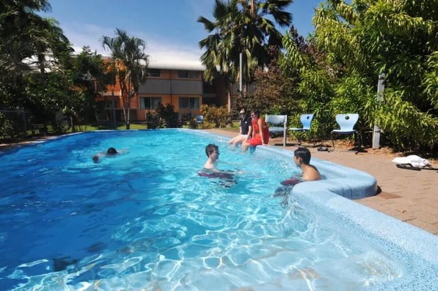 Students relax by outdoor swimming pool exterior at CDU Village Casuarina in Darwin Student Accommodation