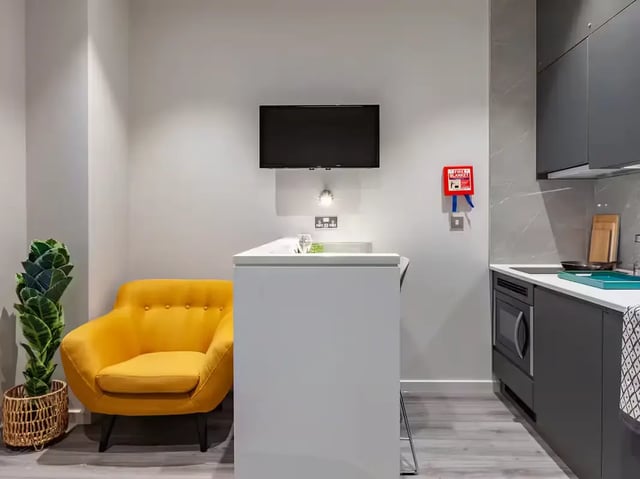 Yellow armchair television and kitchen living area at Grosvenor House in London Student Accommodation