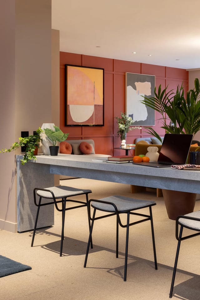 Table with laptop stools plants and artwork living room at The Pepper Mill in Edinburgh Student Accommodation