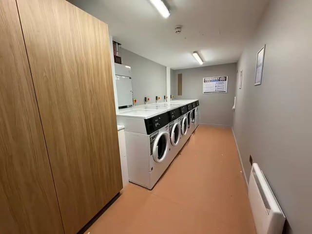 Laundry room with washing machines and large wooden cabinet laundry room at The Pepper Mill in Edinburgh Student Accommodation