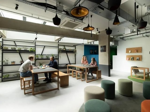 People seated at tables with plants communal area at Element Bermondsey in London Student Accommodation