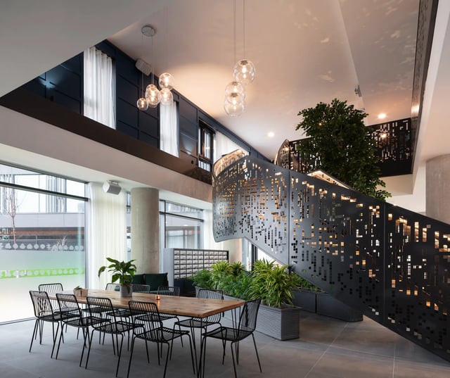 Dining table with chairs modern staircase common area at Aspen Dublin in Dublin Student Accommodation