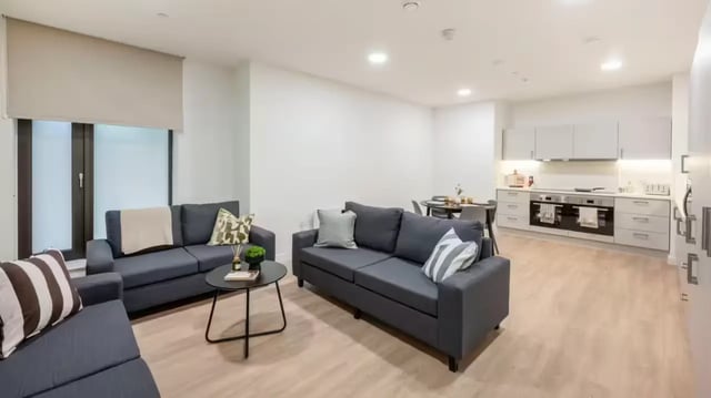 Gray sofas coffee table dining area kitchen living room at St Gabriels in Manchester Student Accommodation