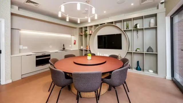 Circular table chairs kitchen cabinets and television communal area at The Aspen in Leicester Student Accommodation