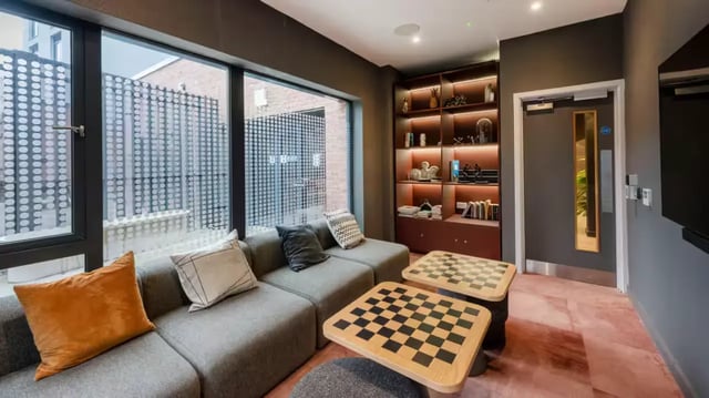 Gray sectional sofa chess tables illuminated shelves lounge at The Aspen in Leicester Student Accommodation