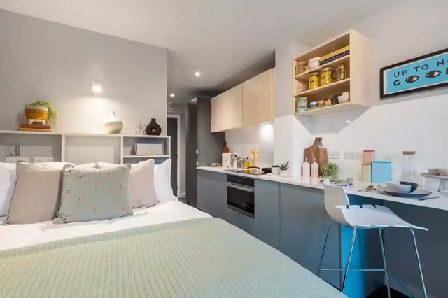 Bed with pillows and kitchen area studio apartment at The Aspen in Leicester Student Accommodation