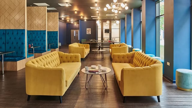 Yellow couches blue booths and tables common area living room at Howard Gardens in Cardiff Student Accommodation