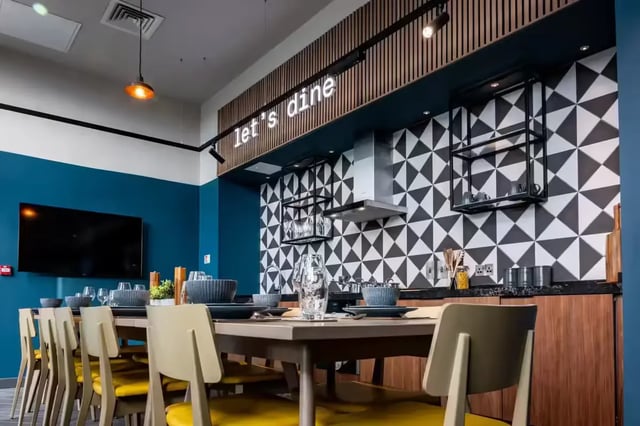 Dining table and chairs with modern kitchen area at Compass in Birmingham Student Accommodation