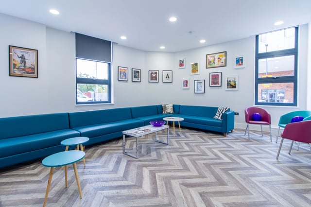 Blue sectional couch with colorful chairs living room at AXO Seven Sisters in London Student Accommodation