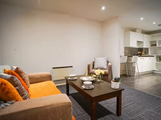 Sofa armchairs coffee table kitchen living room at Gallery Apartments in Glasgow Student Accommodation