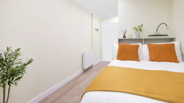 Bed with orange pillows and throw bedroom at St Vincent Studios in Glasgow Student Accommodation