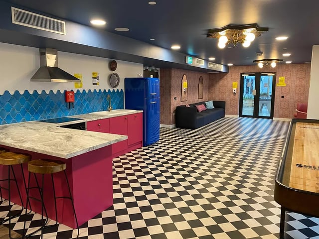 Modern kitchen with pink island couch and shuffleboard common room at Yugo Bailey Point in Bournemouth Student Accommodation