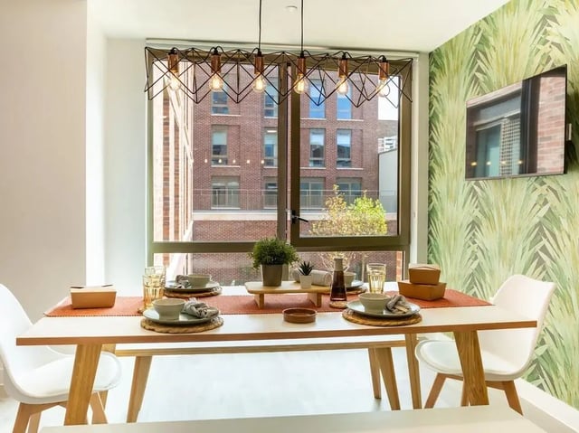 Dining table chairs place settings plant and TV dining area at Promenade Student Living in Brighton Student Accommodation