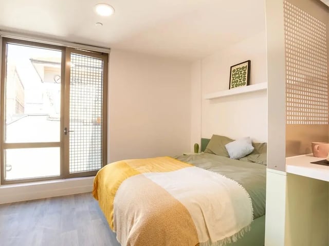 Bed with yellow blanket large window bedroom at Promenade Student Living in Brighton Student Accommodation