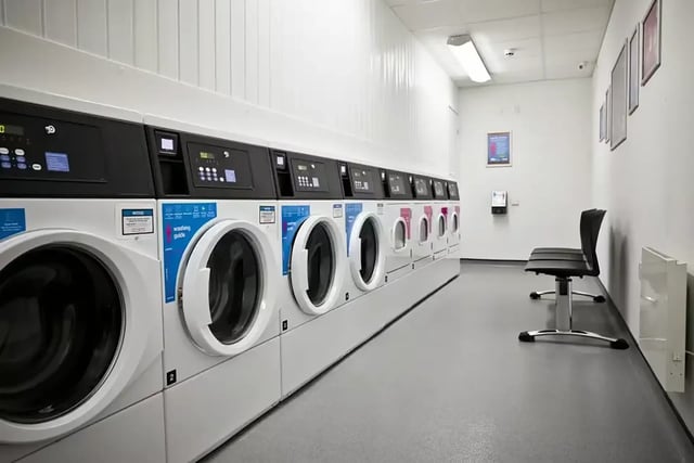 Row of washing machines with chairs laundry room at Friargate Court in Preston Student Accommodation