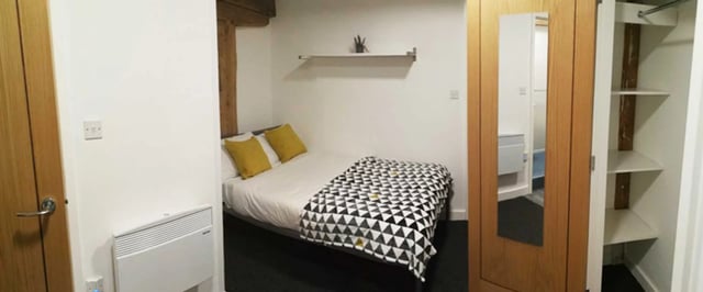 Bed with yellow pillows geometric blanket and wardrobe bedroom at Forest Rise in Loughborough Student Accommodation