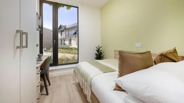 Bed desk wardrobe green wall bedding bedroom at St Gabriels in Manchester Student Accommodation