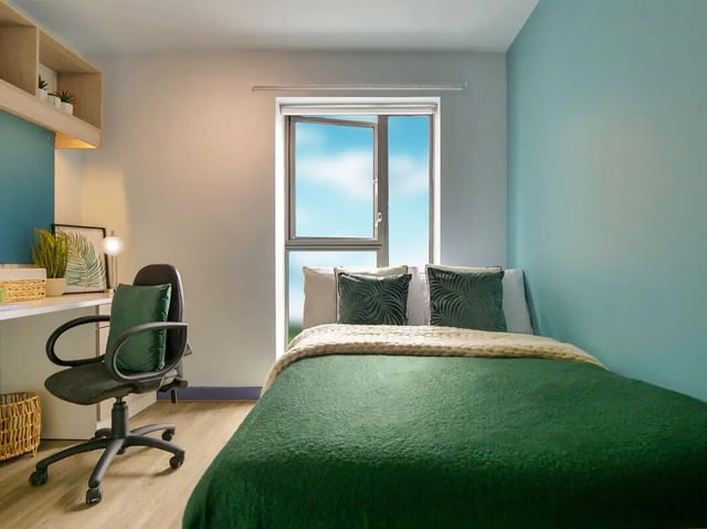 Bed with green blankets and desk with chair bedroom at Bright House in Kingston Upon Thames Student Accommodation