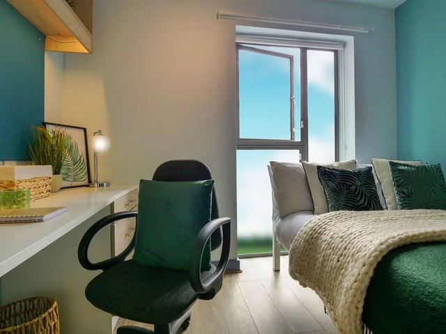 Desk chair, bed with green pillows, window bedroom at Bright House in Kingston Upon Thames Student Accommodation