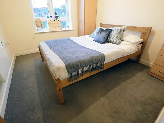 Wooden bed grey throw blue pillows bedroom at Hassells Bridge House in Newcastle Under Lyme Student Accommodation