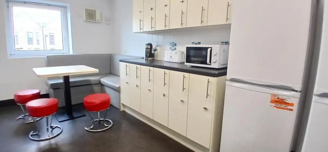 Table booth microwave white cabinets refrigerator kitchen at Hamwic Hall in Southampton Student Accommodation