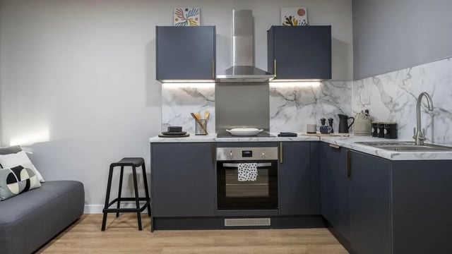Dark grey kitchen with oven stool and couch kitchen at Clyde Court in Glasgow Student Accommodation