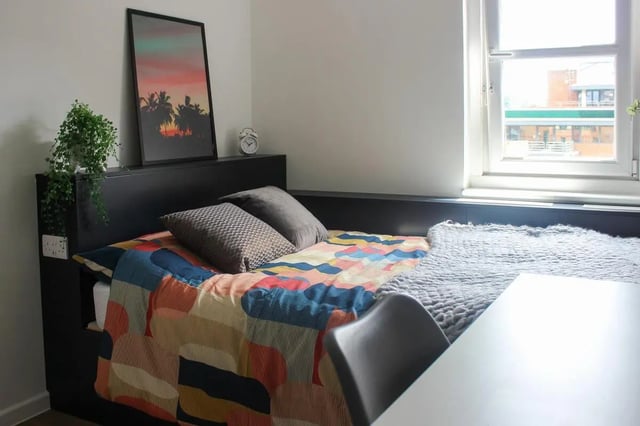 Bed with colorful quilt, pillows, plant, alarm clock Bedroom at The Bridge Guildford in Guildford Student Accommodation
