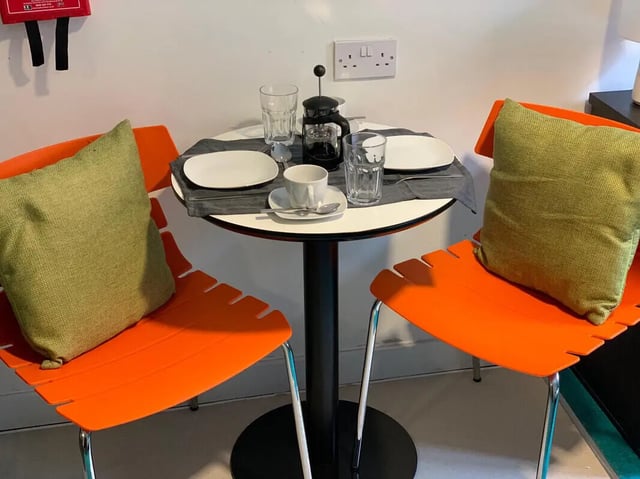 Orange chairs coffee table place settings and french press dining area at Plato House in Liverpool Student Accommodation