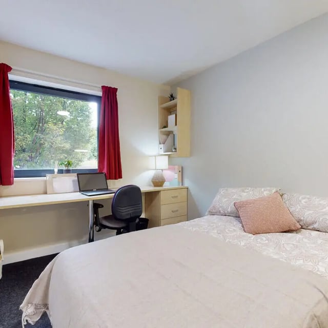 Desk bed and window with red curtains bedroom at The Pinnacles in Sheffield Student Accommodation
