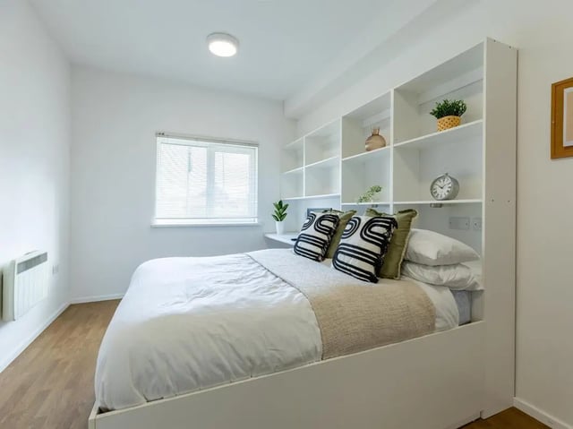 Bed with white linens large white shelving unit Bedroom at St Augustine's House in Plymouth Student Accommodation