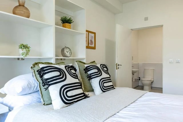 Bed with decorative pillows and view of bathroom interior at St Augustine's House in Plymouth Student Accommodation