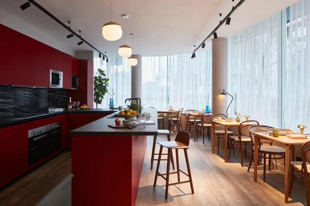 Modern red kitchen island dining tables white curtains living room at Tribu Kingston in Kingston Upon Thames Student Accommodation