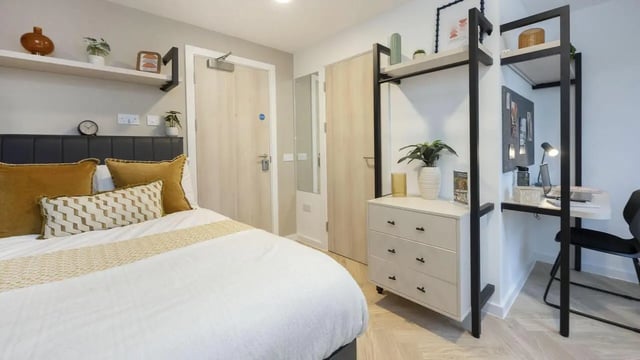 Bed with yellow pillows and desk area bedroom. at Arcadian in Nottingham Student Accommodation