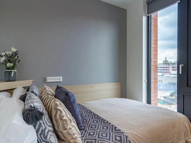 Bed with patterned pillows and cityscape view bedroom at Straits Village in Nottingham Student Accommodation