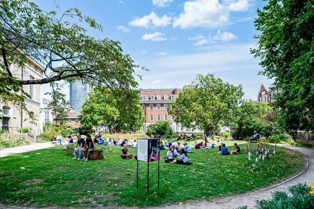 Students relaxing on lawn near brick buildings exterior at AXO Waterloo in London Student Accommodation