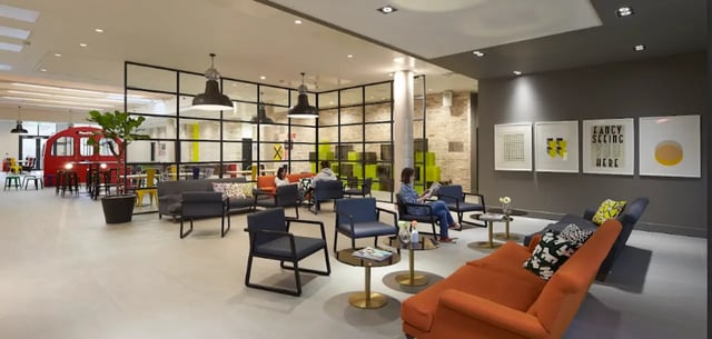 Modern lounge with red tube booth and artwork common area at Spring Mews in London Student Accommodation