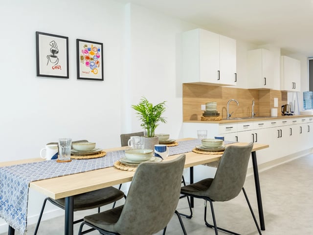 Dining table with place settings and kitchen counter area kitchen at Venti House in London Student Accommodation