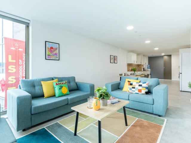 Two blue sofas with colorful cushions and coffee table living room at Venti House in London Student Accommodation
