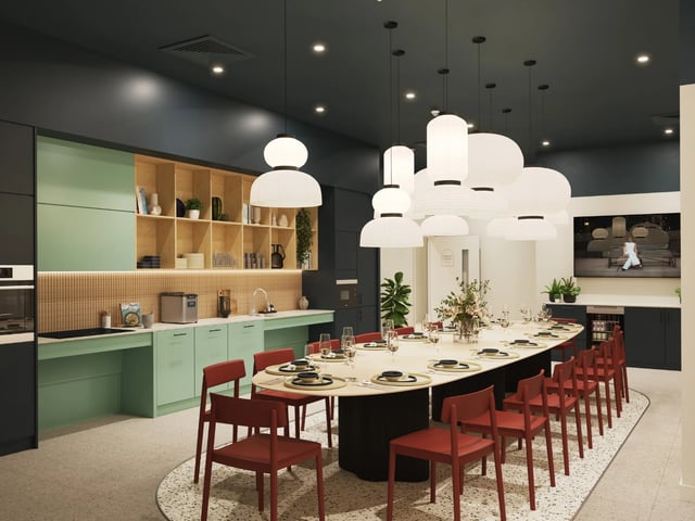 Large oval table red chairs and kitchen area Dining area at Venti House in London Student Accommodation