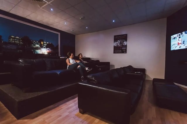 Two women watching television on leather sofas common room at The Junxion Lincoln in Lincoln Student Accommodation