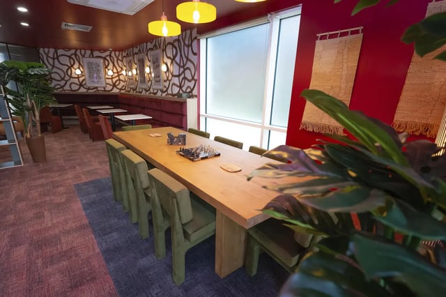Large wooden table green chairs chess board common area at Aparto Arbury Court in Kingston Upon Thames Student Accommodation