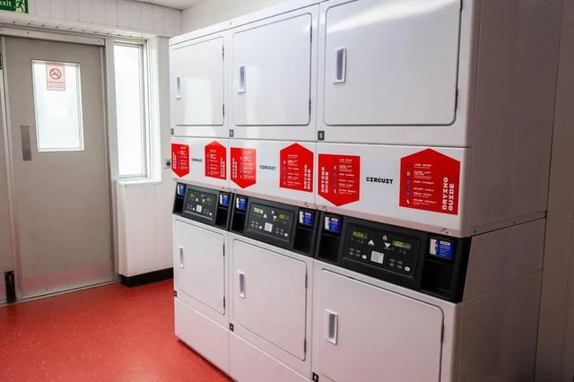 Stacked laundry machines with red drying guides Laundry room at Marybone Student Village 2 in Liverpool Student Accommodation