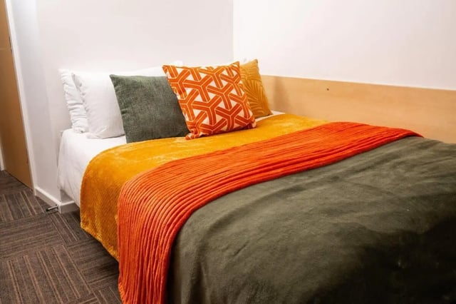 Bed with orange and green blankets and pillows bedroom at Marybone Student Village 2 in Liverpool Student Accommodation