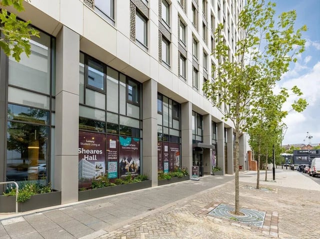 Modern building entrance with trees and signage exterior at Sheares Hall in Newcastle Upon Tyne Student Accommodation