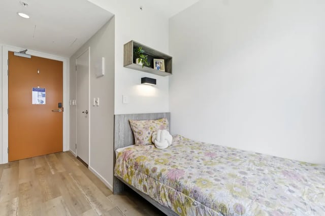 Bed with floral bedding shelf above bedroom at Mayoral Drive Student Accommodation in Auckland Student Accommodation