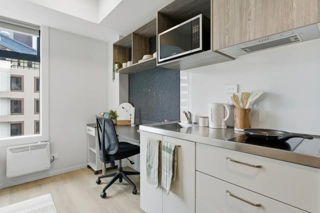 Desk chair kettle microwave and stovetop kitchen at Mayoral Drive Student Accommodation in Auckland Student Accommodation