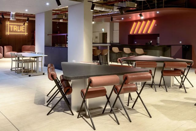 Student lounge with tables chairs and bar area at True Nottingham in Nottingham Student Accommodation