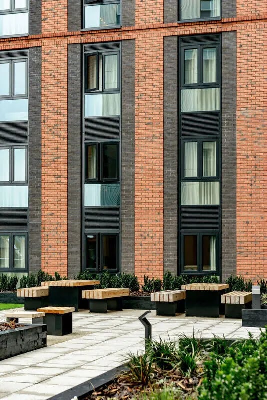 Wooden benches outside brick building exterior at True Nottingham in Nottingham Student Accommodation